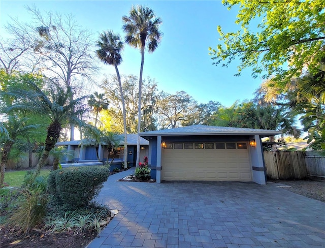 view of front of property with a garage, fence, decorative driveway, and stucco siding