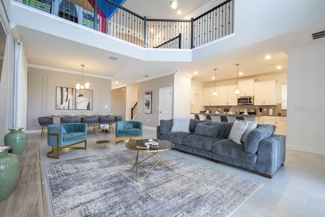 living area featuring a notable chandelier, a high ceiling, baseboards, and crown molding