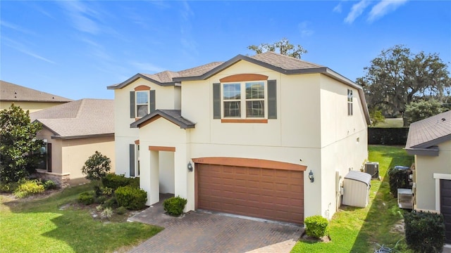 traditional-style home featuring central air condition unit, a garage, decorative driveway, and a front yard