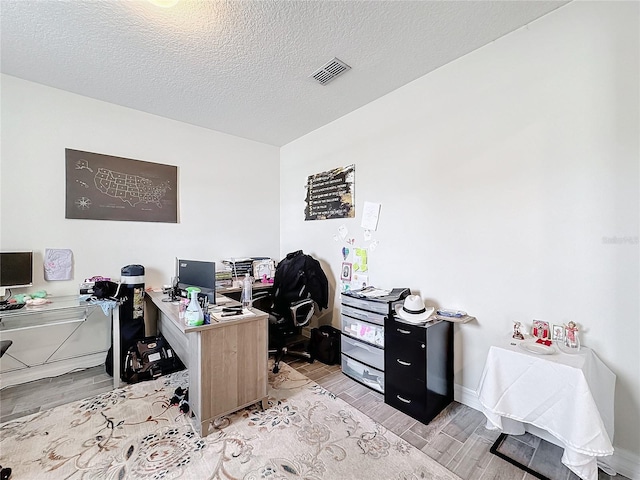 home office with baseboards, visible vents, a textured ceiling, and wood finish floors