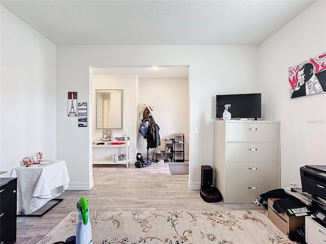 bedroom with a textured ceiling, light wood finished floors, and baseboards