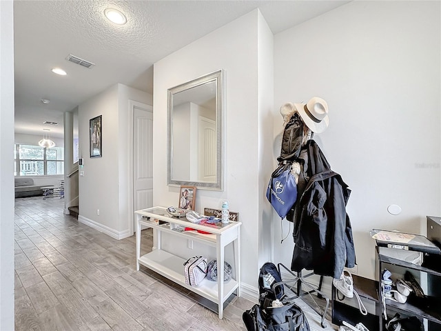 corridor featuring recessed lighting, visible vents, a textured ceiling, wood finished floors, and baseboards