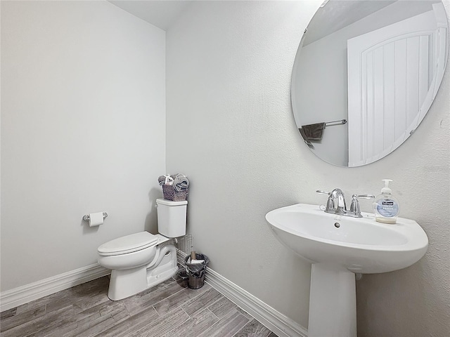 bathroom with baseboards, a sink, toilet, and wood tiled floor