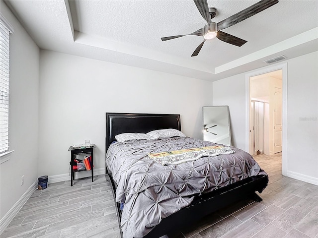 bedroom featuring a textured ceiling, wood finish floors, visible vents, and baseboards