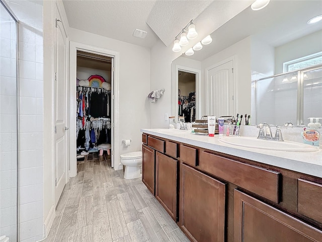 full bath featuring double vanity, wood finished floors, a stall shower, and a sink