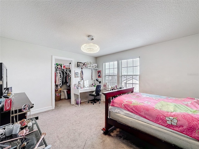 carpeted bedroom featuring a textured ceiling, a spacious closet, a closet, and baseboards