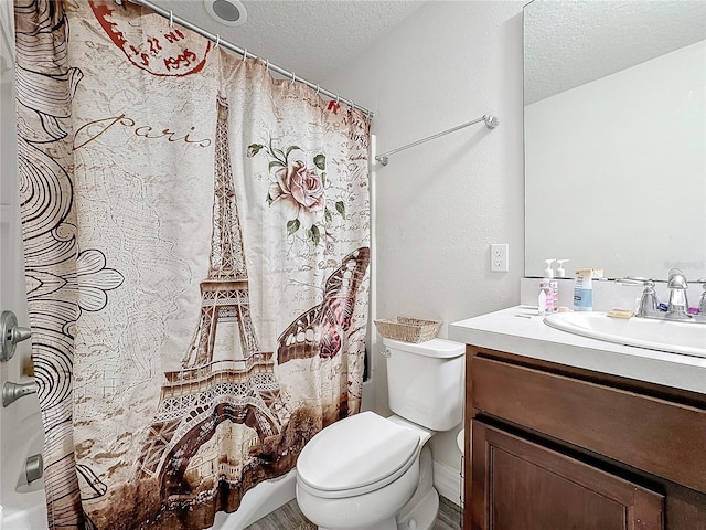 bathroom with a textured wall, toilet, a shower with curtain, a textured ceiling, and vanity