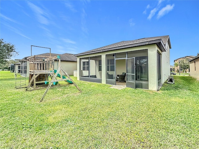 rear view of property featuring a shingled roof, a lawn, a playground, and a sunroom