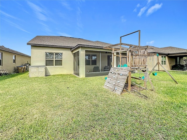 back of house with a playground, a yard, stucco siding, a shingled roof, and a sunroom