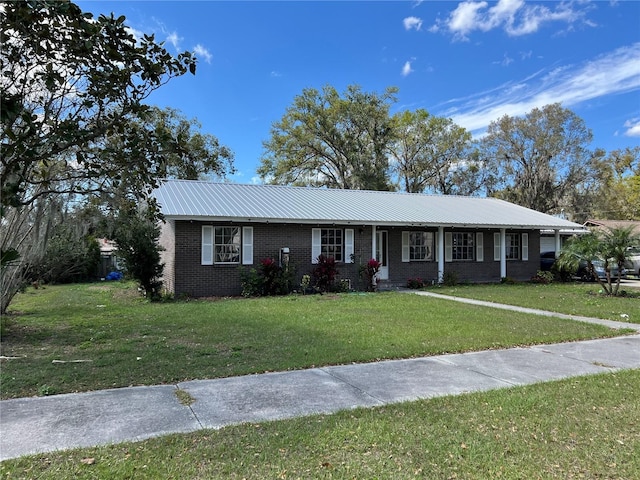 single story home featuring metal roof, brick siding, and a front yard