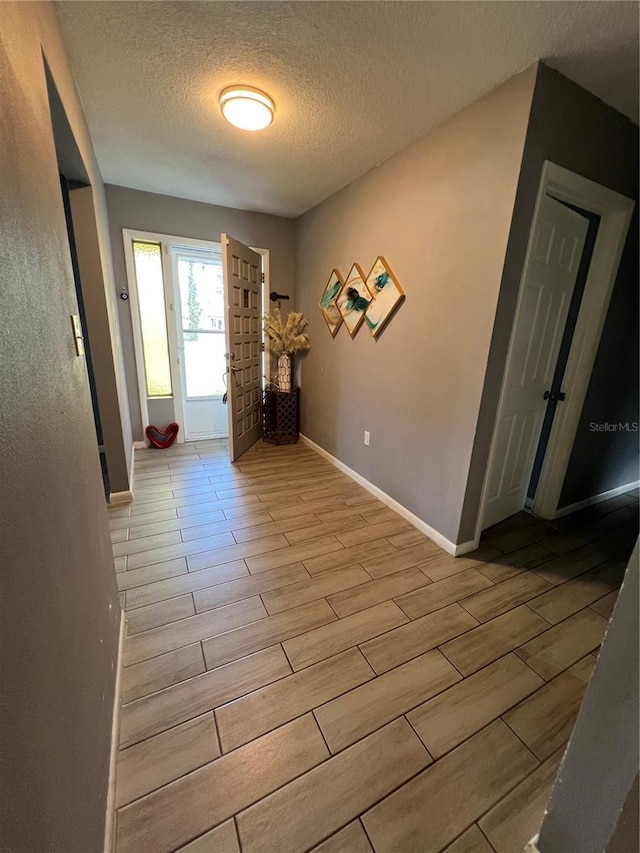 interior space with wood tiled floor, baseboards, and a textured ceiling