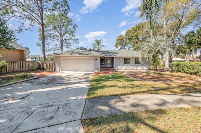 view of front of home featuring an attached garage, fence, driveway, stucco siding, and a front yard