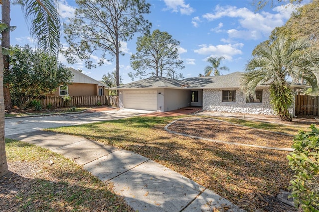 single story home with a garage, concrete driveway, and fence