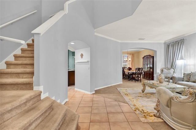 living area with arched walkways, light tile patterned flooring, baseboards, stairs, and crown molding