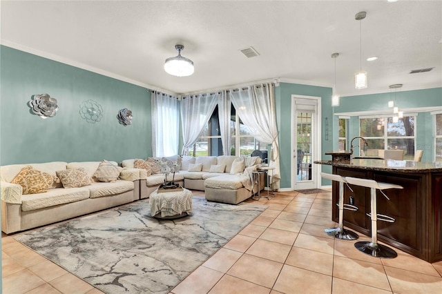 living area featuring ornamental molding, light tile patterned flooring, visible vents, and baseboards