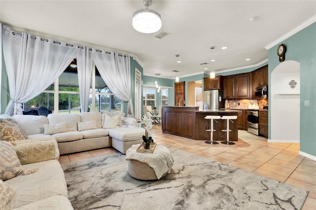 living room featuring baseboards, visible vents, arched walkways, crown molding, and light tile patterned flooring