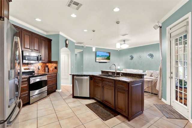 kitchen featuring decorative light fixtures, stainless steel appliances, visible vents, a sink, and an island with sink