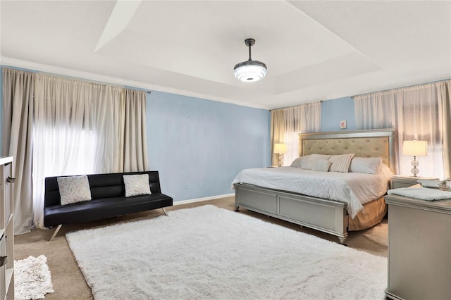 bedroom with a tray ceiling, light colored carpet, and baseboards