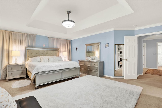 carpeted bedroom featuring ornamental molding, arched walkways, a raised ceiling, and baseboards
