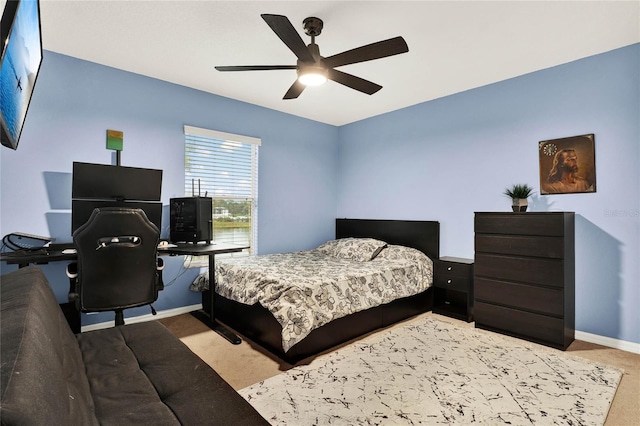 bedroom with light carpet, a ceiling fan, and baseboards