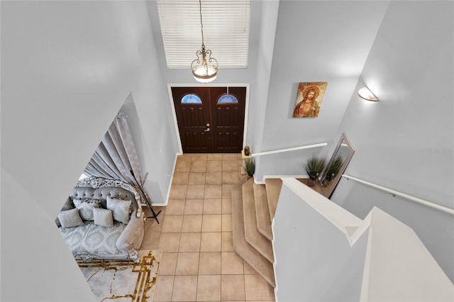 foyer entrance with baseboards, a high ceiling, and tile patterned floors