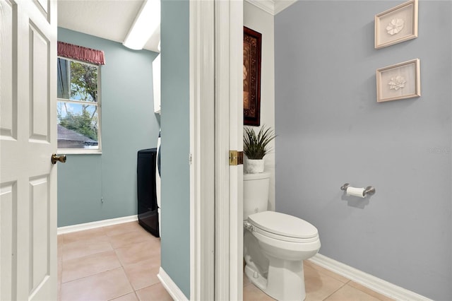 bathroom featuring toilet, washer / dryer, tile patterned flooring, and baseboards