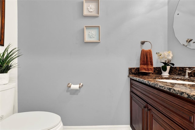 bathroom featuring toilet, baseboards, and vanity