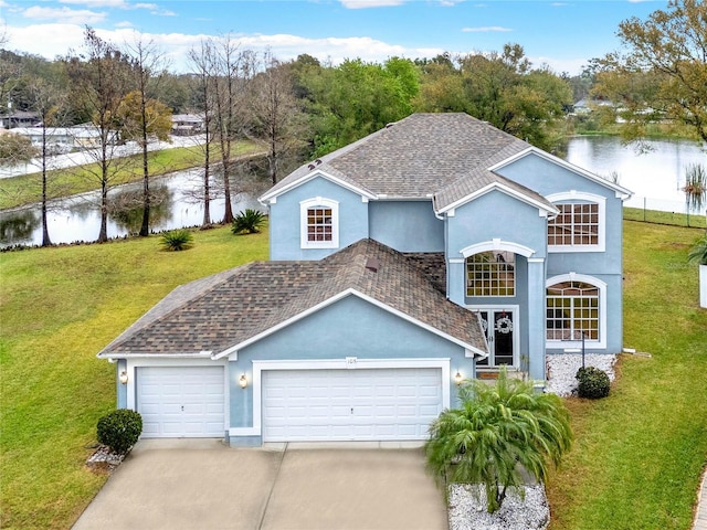 view of front of house with a garage, concrete driveway, roof with shingles, a water view, and a front yard