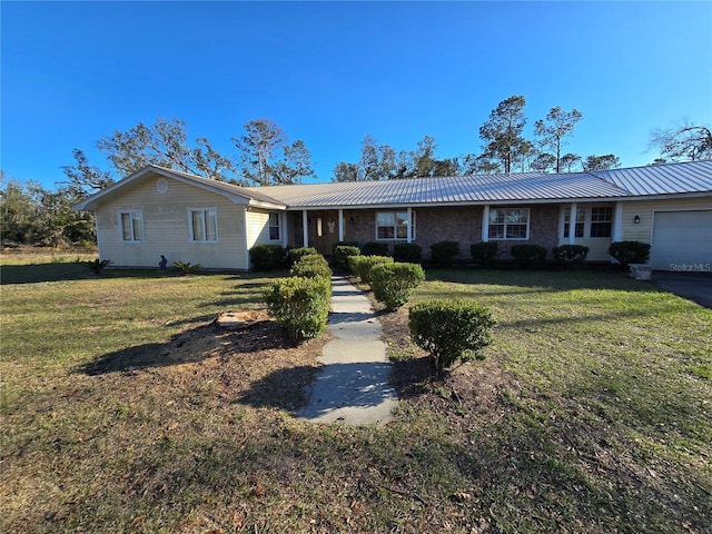 single story home featuring an attached garage, metal roof, and a front yard