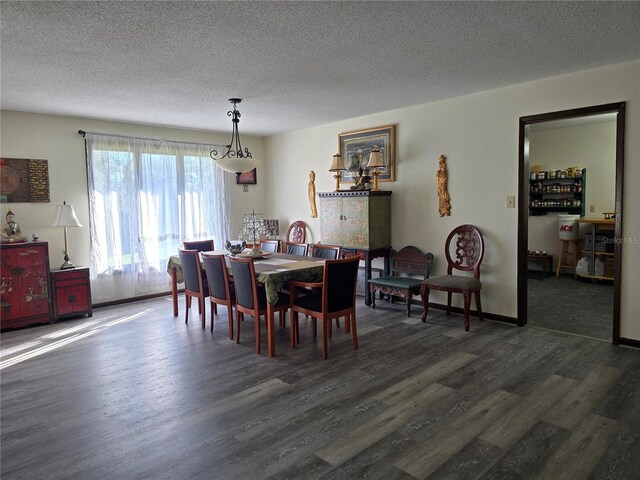 dining room featuring dark wood-style flooring, a textured ceiling, and baseboards