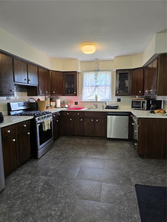 kitchen with light countertops, appliances with stainless steel finishes, a sink, and tasteful backsplash