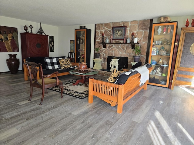 living room featuring a textured ceiling, a fireplace, and wood finished floors