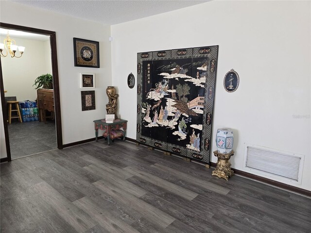 interior details with a chandelier, a textured ceiling, wood finished floors, and visible vents