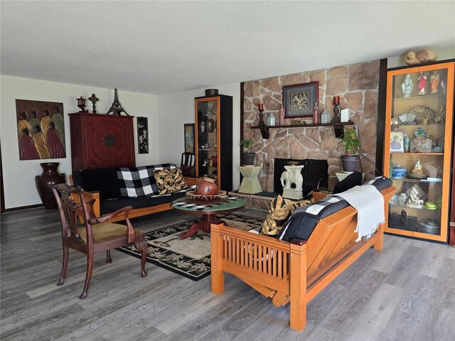 living area featuring a textured ceiling, a fireplace, and wood finished floors