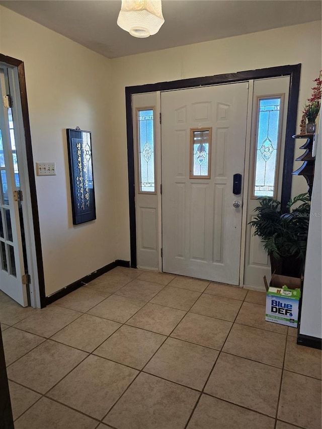 entrance foyer with a healthy amount of sunlight, light tile patterned floors, and baseboards