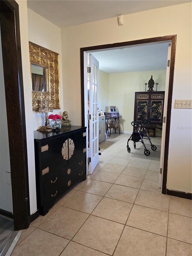 corridor featuring baseboards, french doors, and light tile patterned flooring