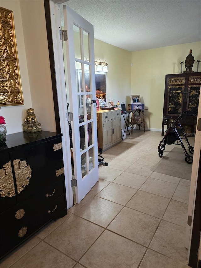 interior space featuring a textured ceiling, french doors, and light tile patterned flooring