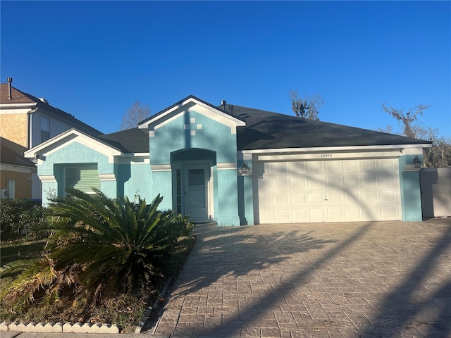 ranch-style home with decorative driveway, an attached garage, and stucco siding