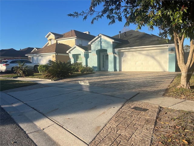 view of front of property featuring a garage, decorative driveway, and stucco siding