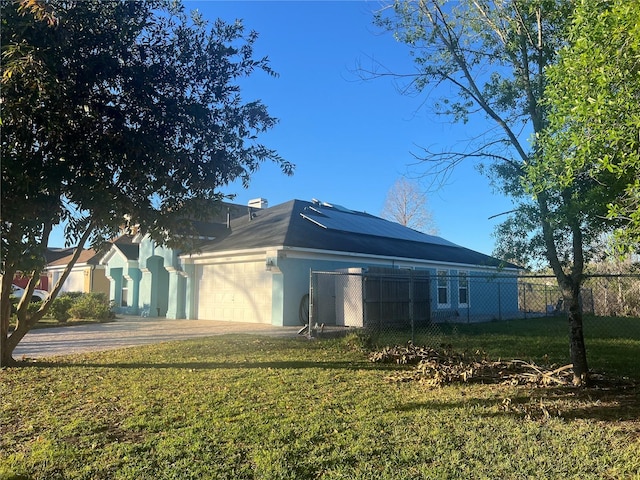 view of side of home featuring a garage, fence, a lawn, and stucco siding