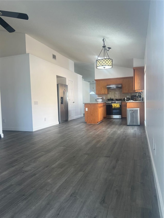 kitchen featuring stainless steel appliances, open floor plan, backsplash, brown cabinetry, and dark wood finished floors