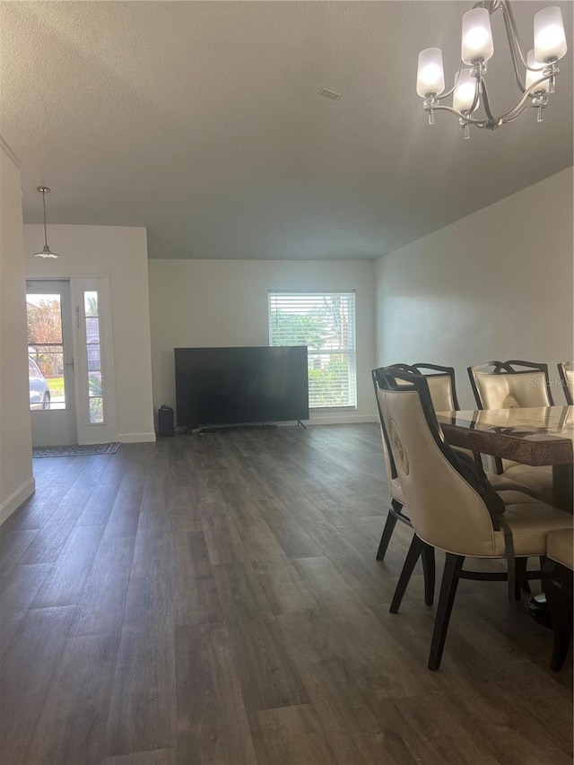 unfurnished dining area featuring baseboards, dark wood-style flooring, a textured ceiling, and a notable chandelier