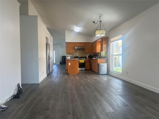 kitchen with under cabinet range hood, stainless steel appliances, a kitchen island, open floor plan, and decorative backsplash