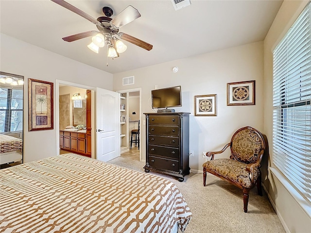 bedroom featuring light carpet, baseboards, visible vents, and ensuite bathroom