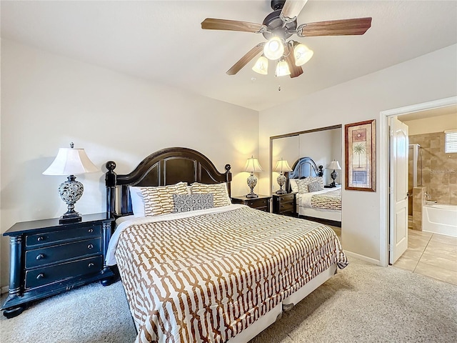 bedroom featuring ceiling fan, light colored carpet, baseboards, a closet, and ensuite bath