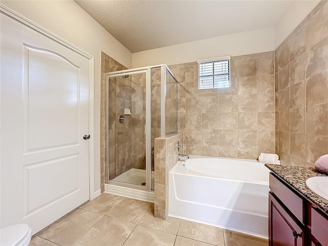 full bathroom featuring a textured ceiling, vanity, a bath, tile patterned floors, and a stall shower