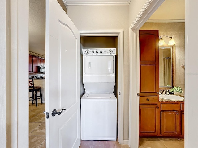 clothes washing area with laundry area, stacked washer / dryer, light tile patterned flooring, and a sink