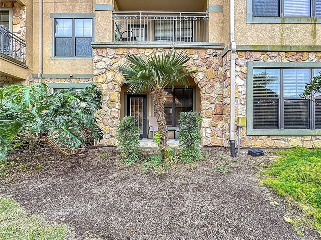 doorway to property with stone siding and stucco siding