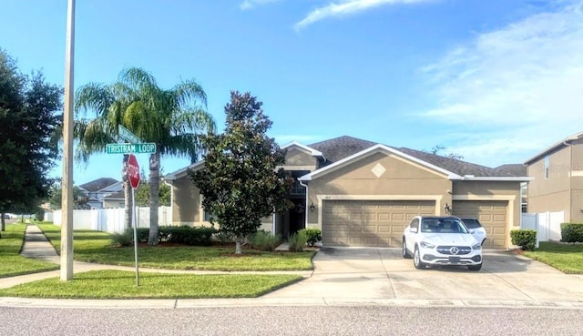 view of front of property with a garage, driveway, fence, a front yard, and stucco siding