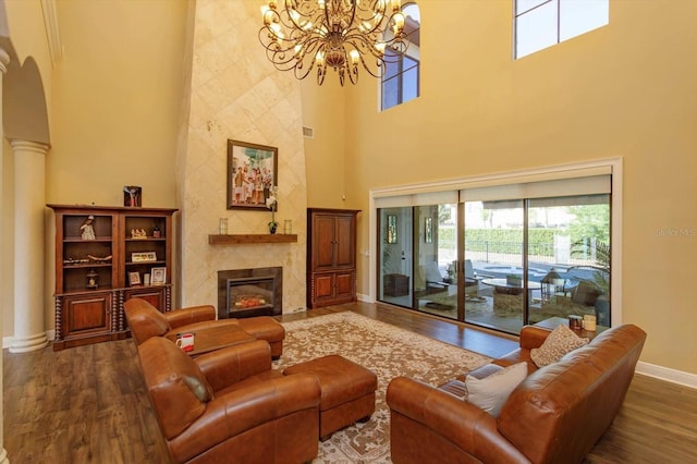 living area featuring baseboards, arched walkways, a towering ceiling, a premium fireplace, and wood finished floors